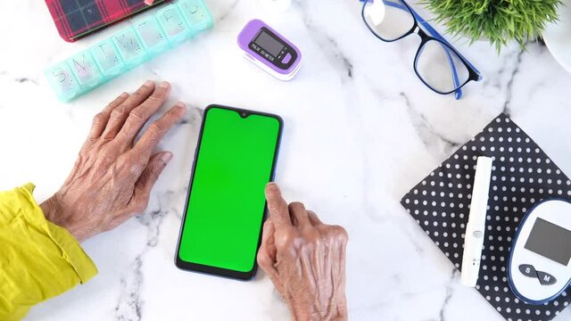 senior women using smart phone and glucometer on table 