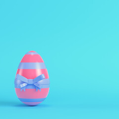 Pink easter egg with bow on bright blue background in pastel colors