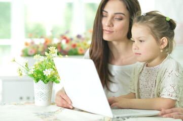 happy mother and daughter using laptop together