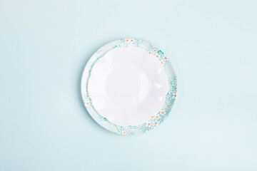 Spring festive minimal composition with two empty beautiful plates on center of light blue backdrop with copy space.