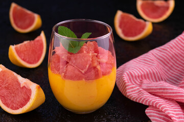 Cream Kurd from grapefruit with a glass on a black background.
Close-up.