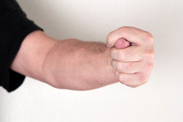 A man hand clenched into a fist shows a fig