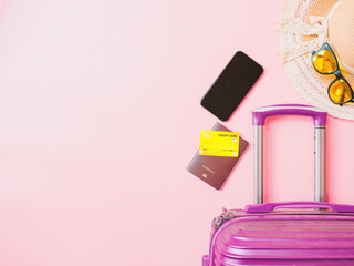 summer travel concept from credit card and suitcase with summer collection on pink background.