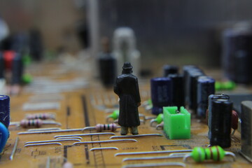 small chracter of a spy standing on cumputer hardware parts 