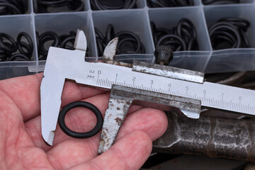 Measuring the diameter of the rubber O-ring with a caliper. An old measuring tool and a set of...