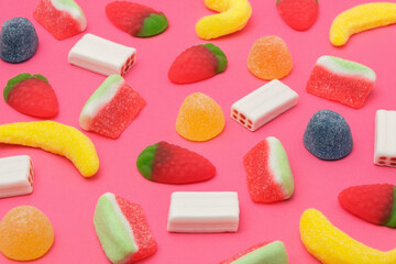Colorful candy variety pattern on a pink background. Tasty gummy candies