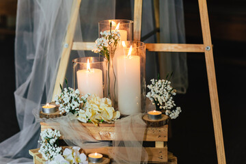 Wedding floral decoration with candles in glasses on wooden boxes