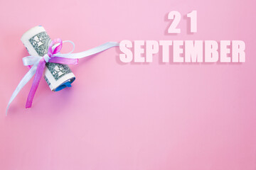 calendar date on pink background with rolled up dollar bills pinned by pink and blue ribbon with copy space. September 21 is the twenty first day of the month