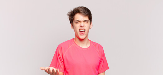 young boy looking angry, annoyed and frustrated screaming wtf or what’s wrong with you