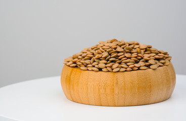  Brown lentils in wooden container. Paste your text.