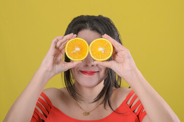 Happy girl with slices of oranges on her eyes.