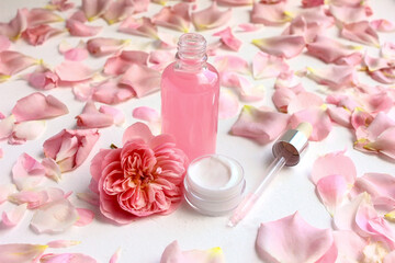 Skin care cosmetics. Rose water whey and face cream on the background of rose petals.
