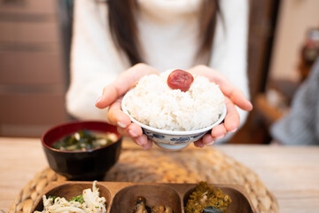お茶碗に入ったお米を食べる女性