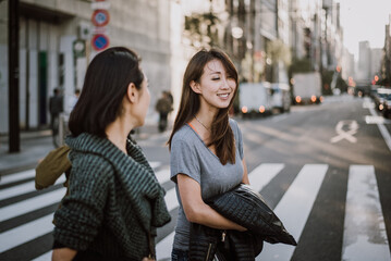 Two japanese women around in Tokyo during daytime. Making shopping and having fun