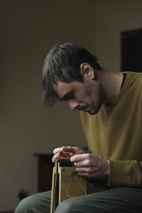 Man with needle sewing leather in workshop. The tanner sews the leather workpieces. Handmade in a...