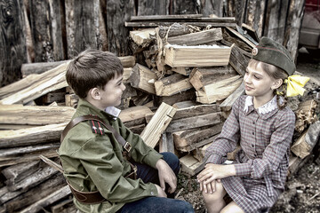 Postcard, stylized as vintage for the Victory Day. A boy in a military uniform and a girl in an old dress. The theme of May 9, Victory Day in Russia. Soft selective focus, added noise