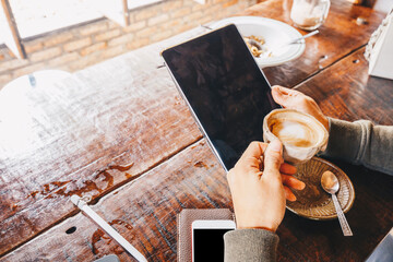 Man shows screen of digital blank tablet device over a wooden with coffee