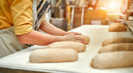 Bakery food factory, fresh food production. The baker is at the work table and makes bread....
