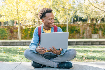 African American man works with his laptop sitting in a park