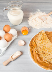 ingredients for making pancakes. flour, eggs, milk, honey. fresh thin pancakes on a wooden table 