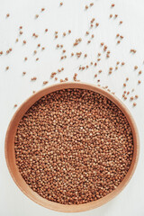 Buckwheat in wooden bowl on white background. Top view. Copy, empty space for text