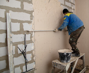 A worker plasters the walls in the room.