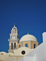 Whitewashed walls, tower and blue dome of one of the many churches on Santorini