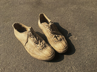 Pair of old white vintage canvas sneakers shoes on cement ground.