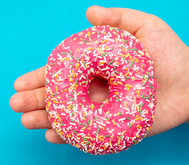 Red donut in hand on a blue background.