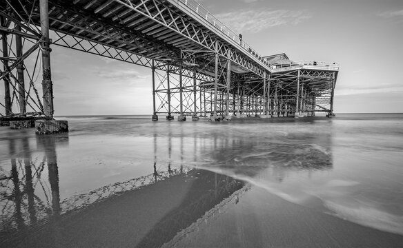 Black and white long exposure photo of a Victorian pier on a sandy beach