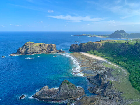 Rocky coastline photo of Green Island, Taiwan on a sunny day with turquoise ocean, in the frame is some rocks in the shape of a pug dog and a sleeping beauty