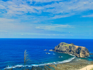 Rocky coastline photo of Green Island, Taiwan on a sunny day with turquoise ocean, in the frame is some rocks in the shape of a pug dog