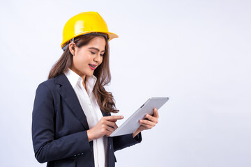 Confident architect Asian woman wearing black suit and yellow safety helmet using tablet computer standing isolated on gray background.