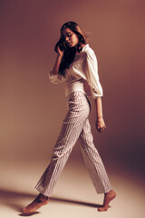 Young woman walking in striped pants and white top