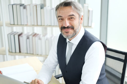 Smiling Smart Caucasian senior manager and businessman in black suit relaxing in social media online for contack to businesspeople on smartphone at workspace at modern office.