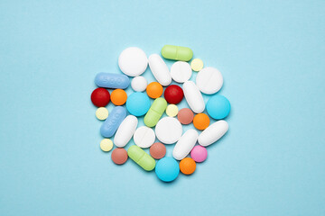 Colorful heap of pills on blue background. Assorted pharmaceutical medicine pills. Medicine concept.