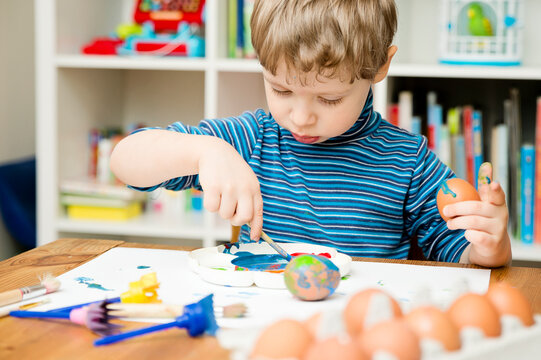 Happy Easter. 3 years boy painting Easter eggs. Religious holiday. Early education and artistic pre-school activities.