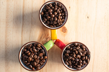 red, green, yellow cups with coffee beans on wood