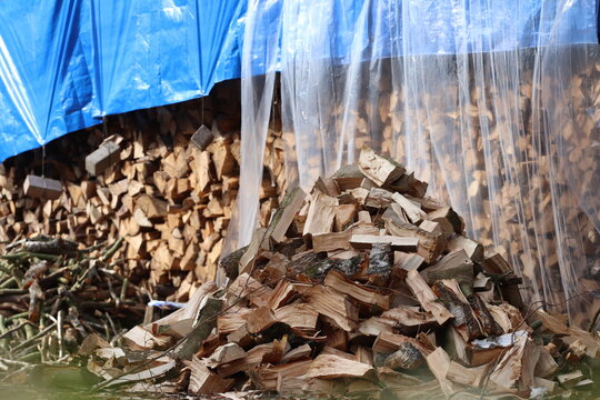 Fresh hacked firewood in woodpile covered with tarpaulin. German countryside,  