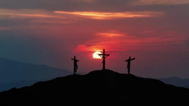 Silhouettes of three crosses on top of a hill at sunset. 
Concept of the Crucifixion of Christ.