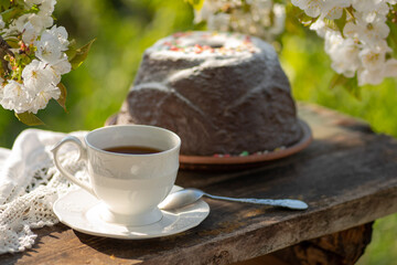 Elegant cup, pudding, cherry blossom branches, wooden table. Outdoor breakfast, picnic, brunch, spring mood