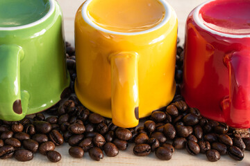 upside down red, green, yellow cups with coffee beans on wood