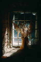 art photography old dried ears of wheat, dried flowers in a vase by the window. Beautiful hard light, rustic style, brick wall with sun shadows