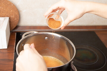 Women's hands add seasoning ginger cinnamon for making gingerbread
