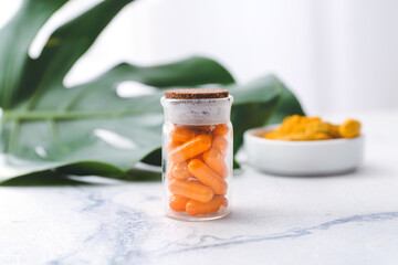 Bottle with turmeric pills on light background