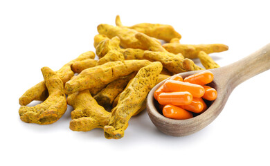 Spoon with pills and turmeric roots on white background