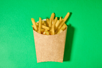 Paper box with tasty french fries on color background