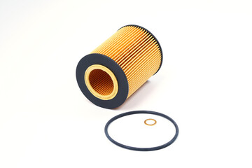 The oil filter lies with a sealing ring on a white background. Replacement filter cartridge for cleaning oil of the car with gasket.