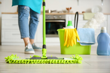 Young woman mopping floor in kitchen