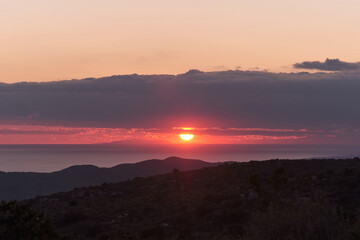 Amazing sunset with colorful clouds, darker mountains in the foreground, nature background.